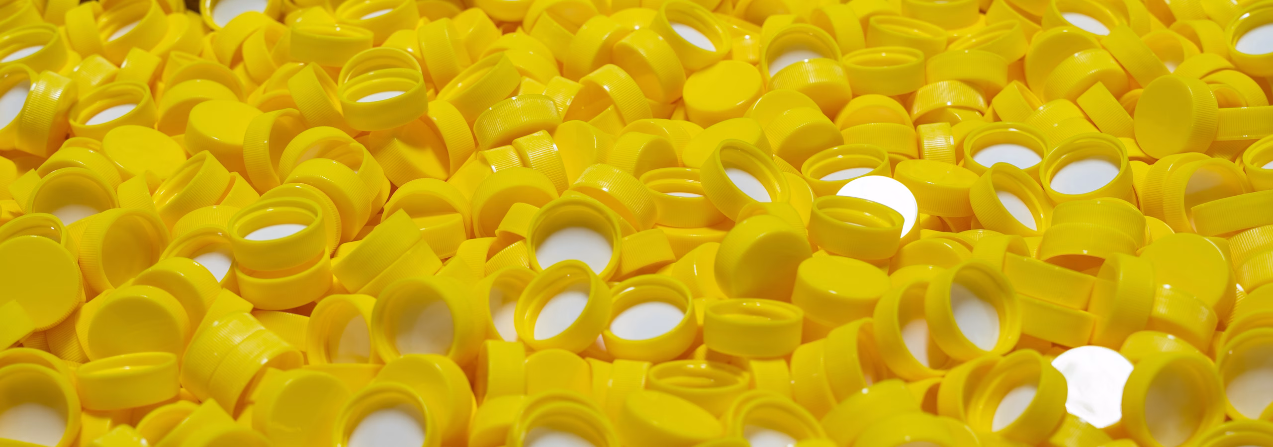 Yellow bottle caps ready for product filling and contract bottling at Custom Bottling & Packaging.